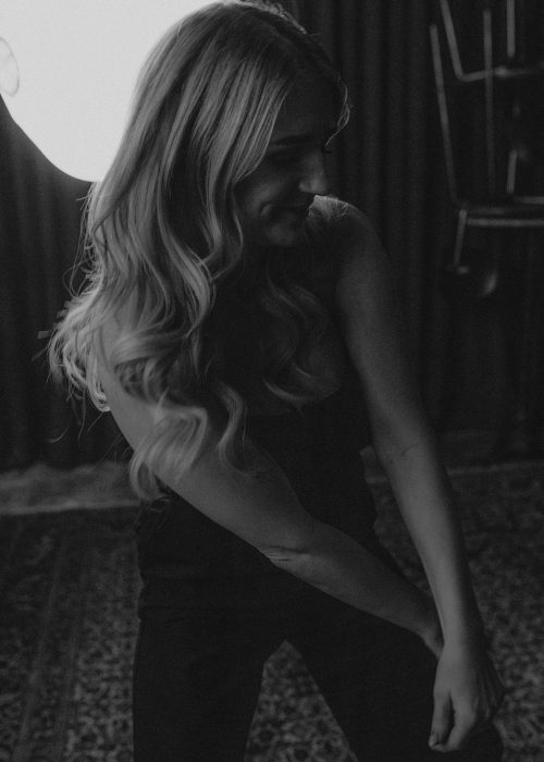 Künstlerisches Schwarz-Weiß-Foto von Laura Ritter im Seitenprofil, stimmungsvoll ausgeleuchtet vor dunklem Hintergrund.